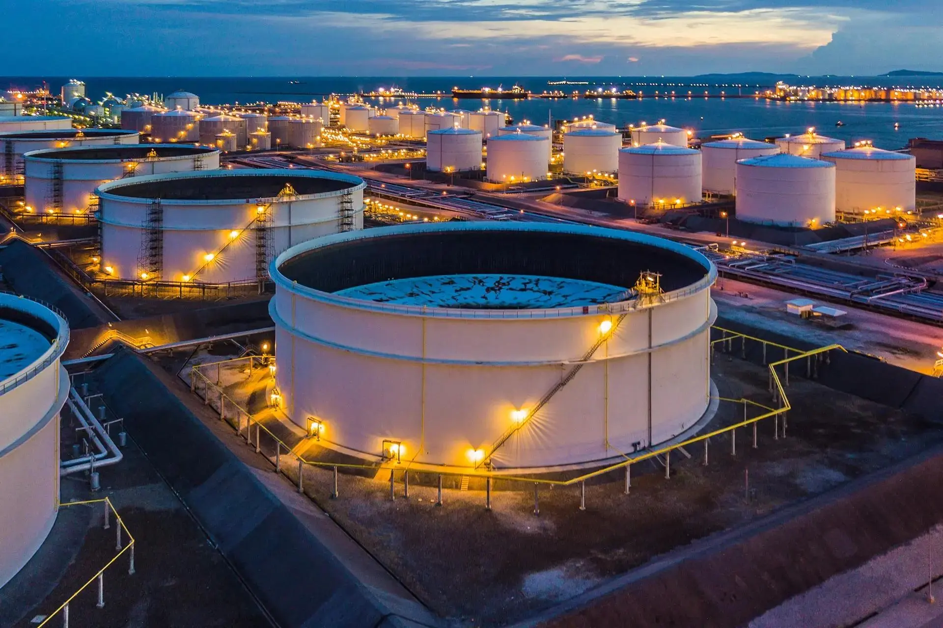 Illuminated coastal petroleum terminal at dusk